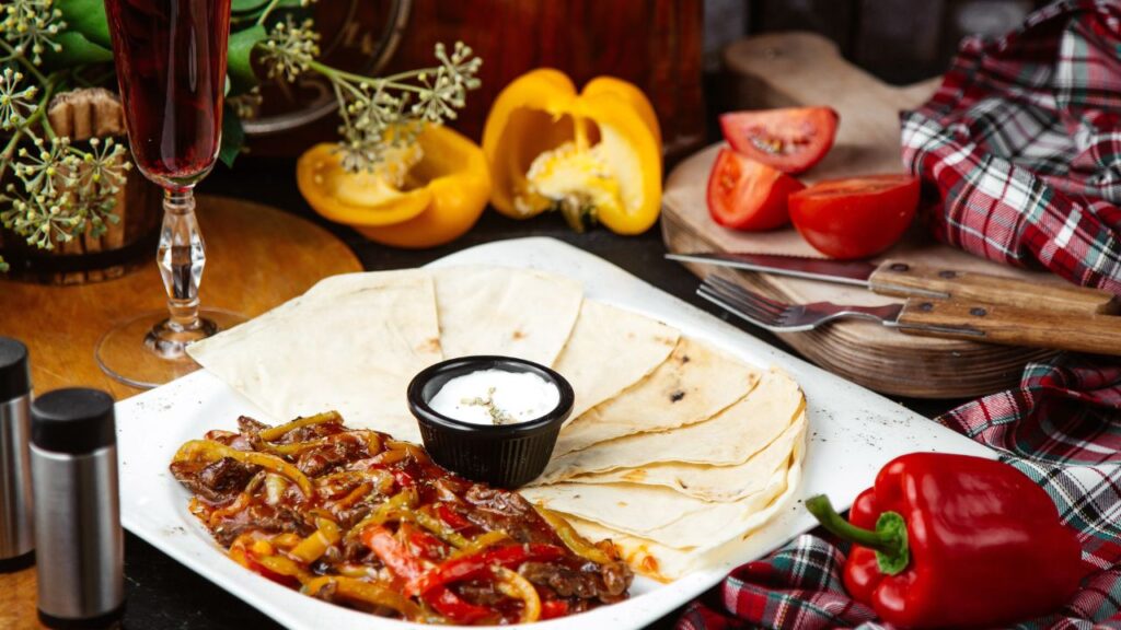 A beautifully assembled chicken fajita on a warm tortilla, topped with guacamole, sour cream, and salsa