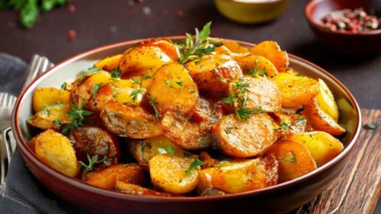 A bowl of creamy roasted potato salad garnished with fresh herbs and served on a rustic table.